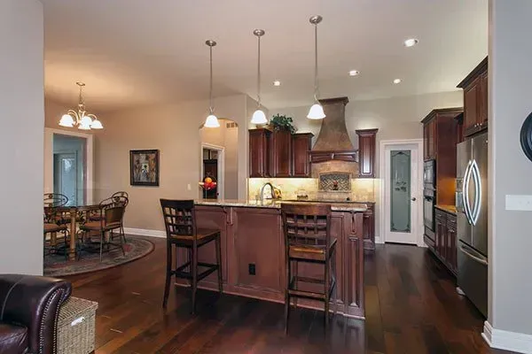 Modern kitchen with dark wood cabinets, island seating, stainless appliances, and an adjacent dining area.