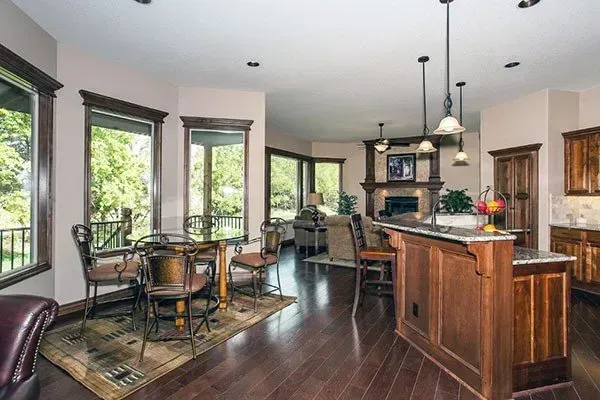 Bright modern kitchen with dark wood floors, large windows, barstools, and a center island