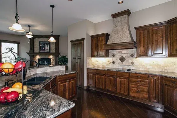 Modern kitchen with dark wood cabinets, granite countertops, and a large stainless range hood.