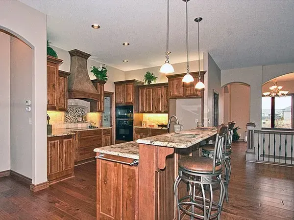 Spacious kitchen with wood cabinets, granite island, pendant lights, and hardwood floors