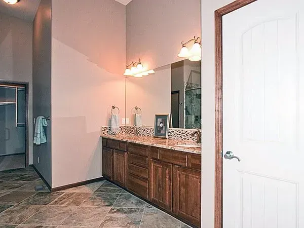 Bathroom with granite vanity, large mirror, wall lights, and tiled floor; closet visible at left.