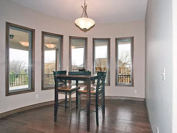 Empty dining room with tall windows, dark wood table, and pendant light.
