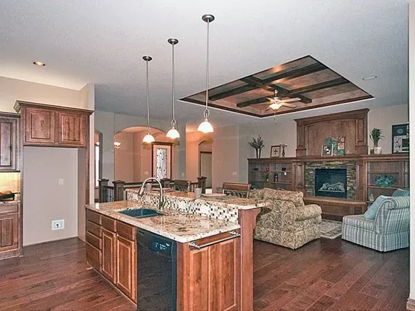 Open-plan kitchen and living room with wood floors, island, pendant lights, and fireplace seating area