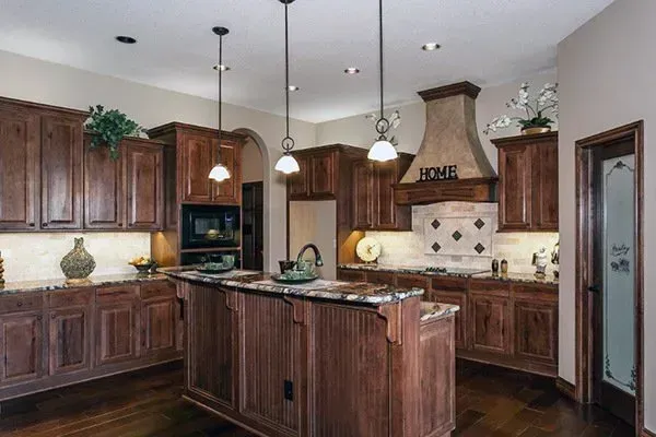 Spacious kitchen with dark wood cabinets, granite island, and beige tile backsplash.