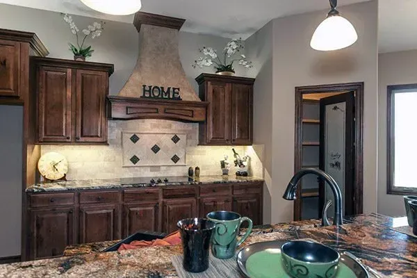 Modern kitchen with dark wood cabinets, granite island, and pendant lights