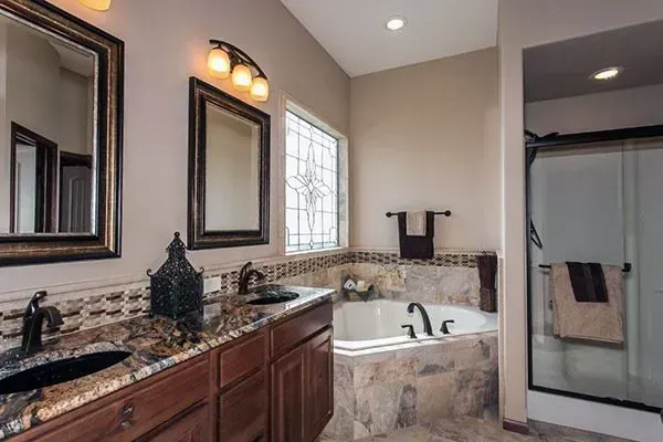 Modern bathroom with double vanity, large mirror, and corner soaking tub with tiled shower.