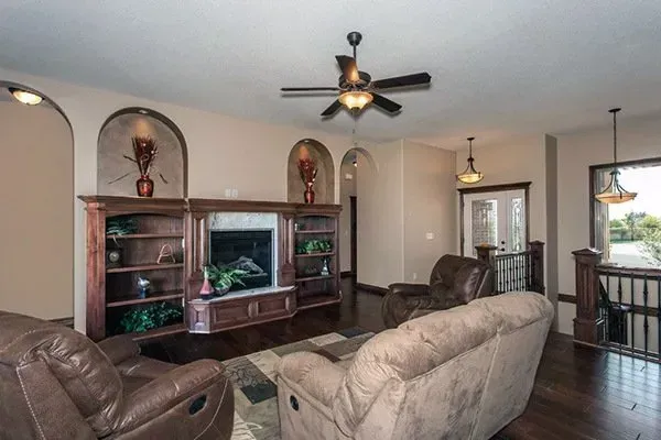 Spacious living room with leather sofas, ceiling fan, and large TV cabinet in neutral tones.