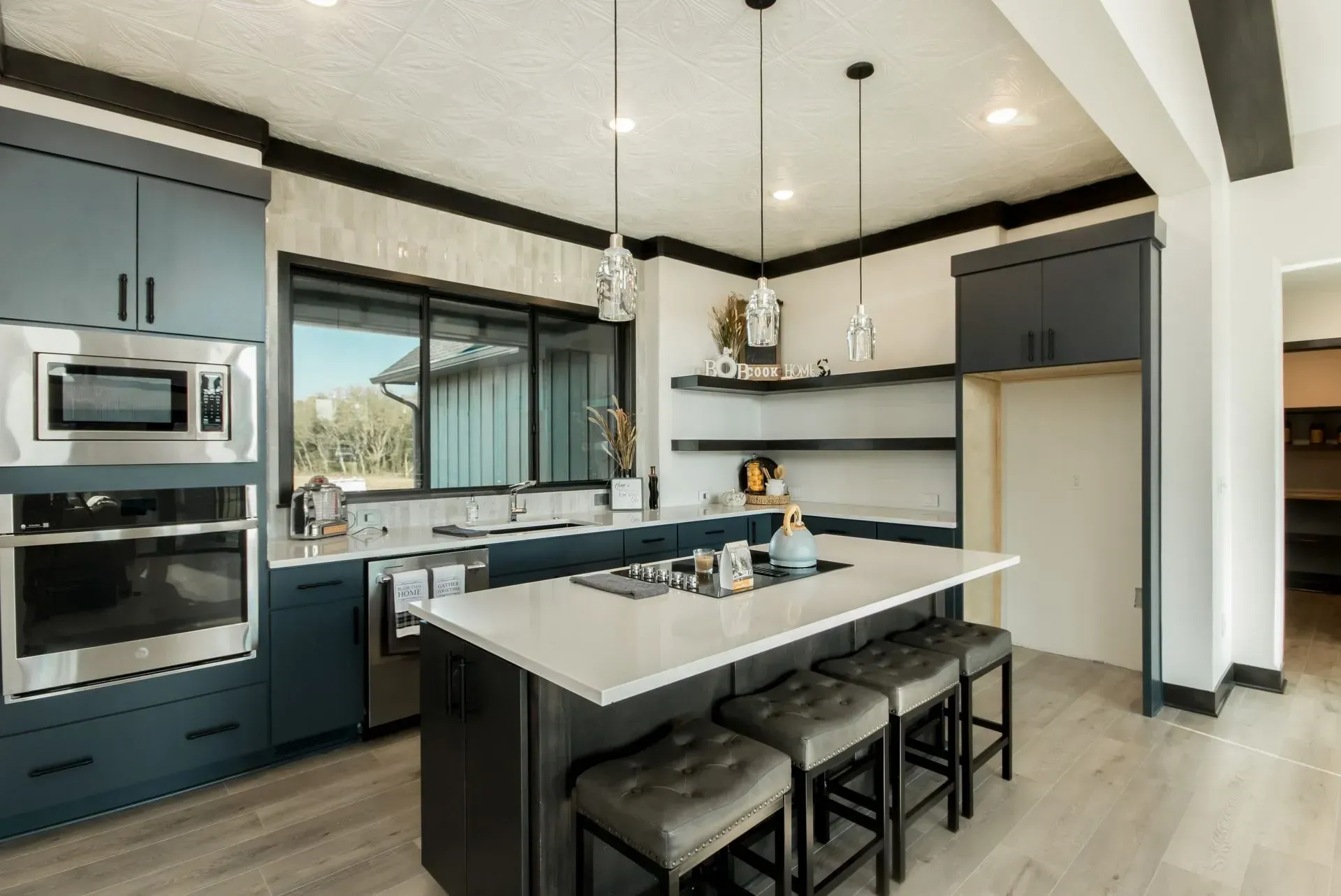 Modern kitchen with navy cabinets, white countertops, island seating, and stainless steel appliances.