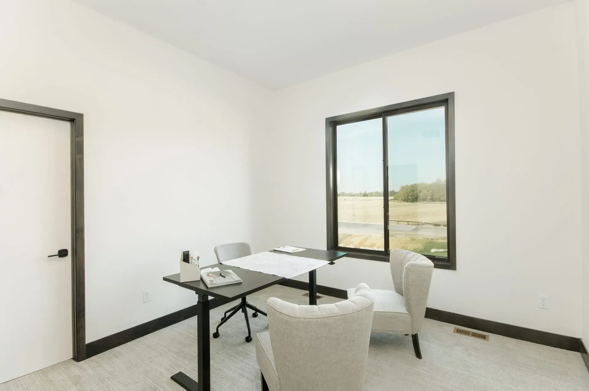 Bright dining room with glass table, white chairs, and a large window overlooking a landscape.