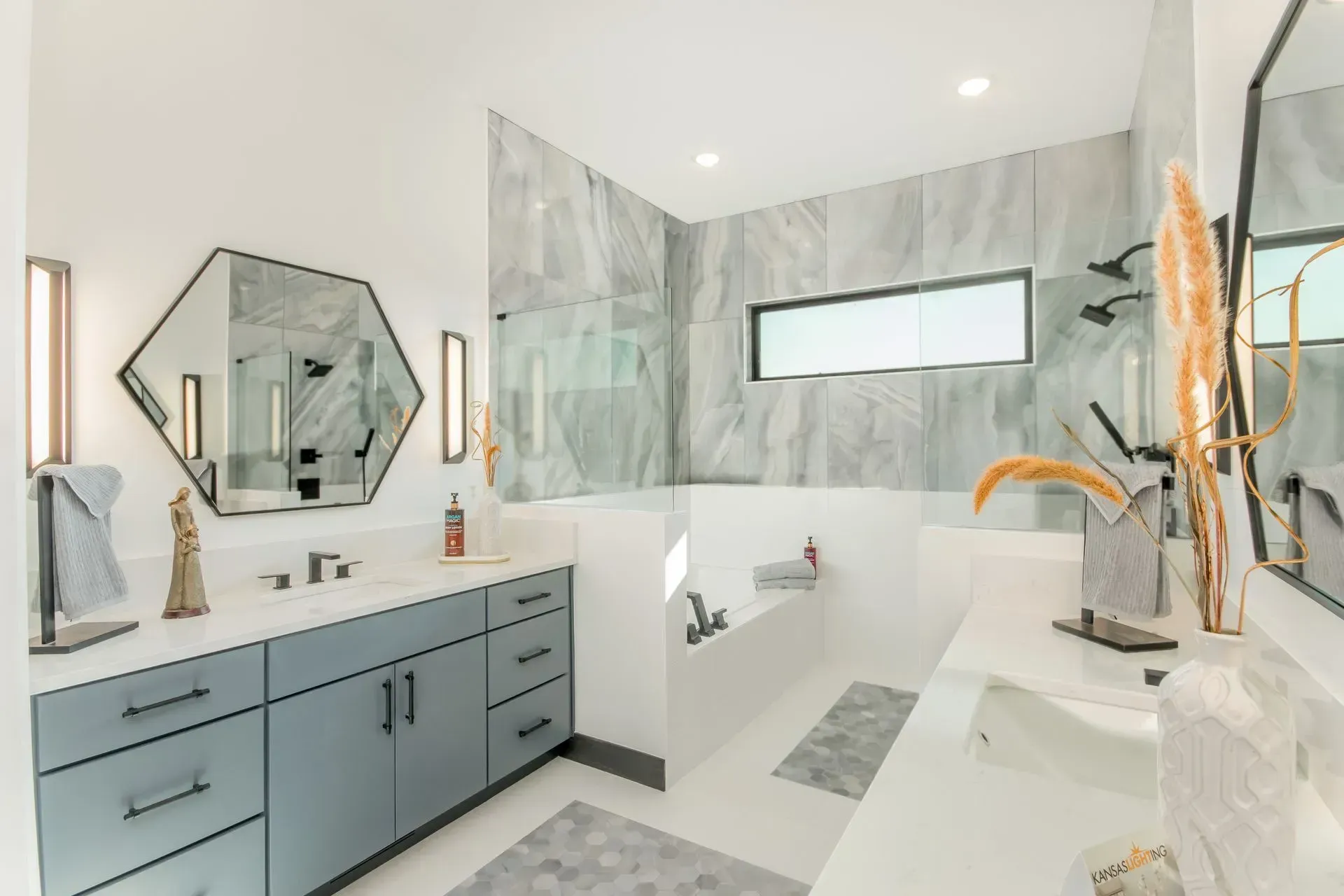 Modern bathroom with marble tile, gray vanity, large mirror, and freestanding tub