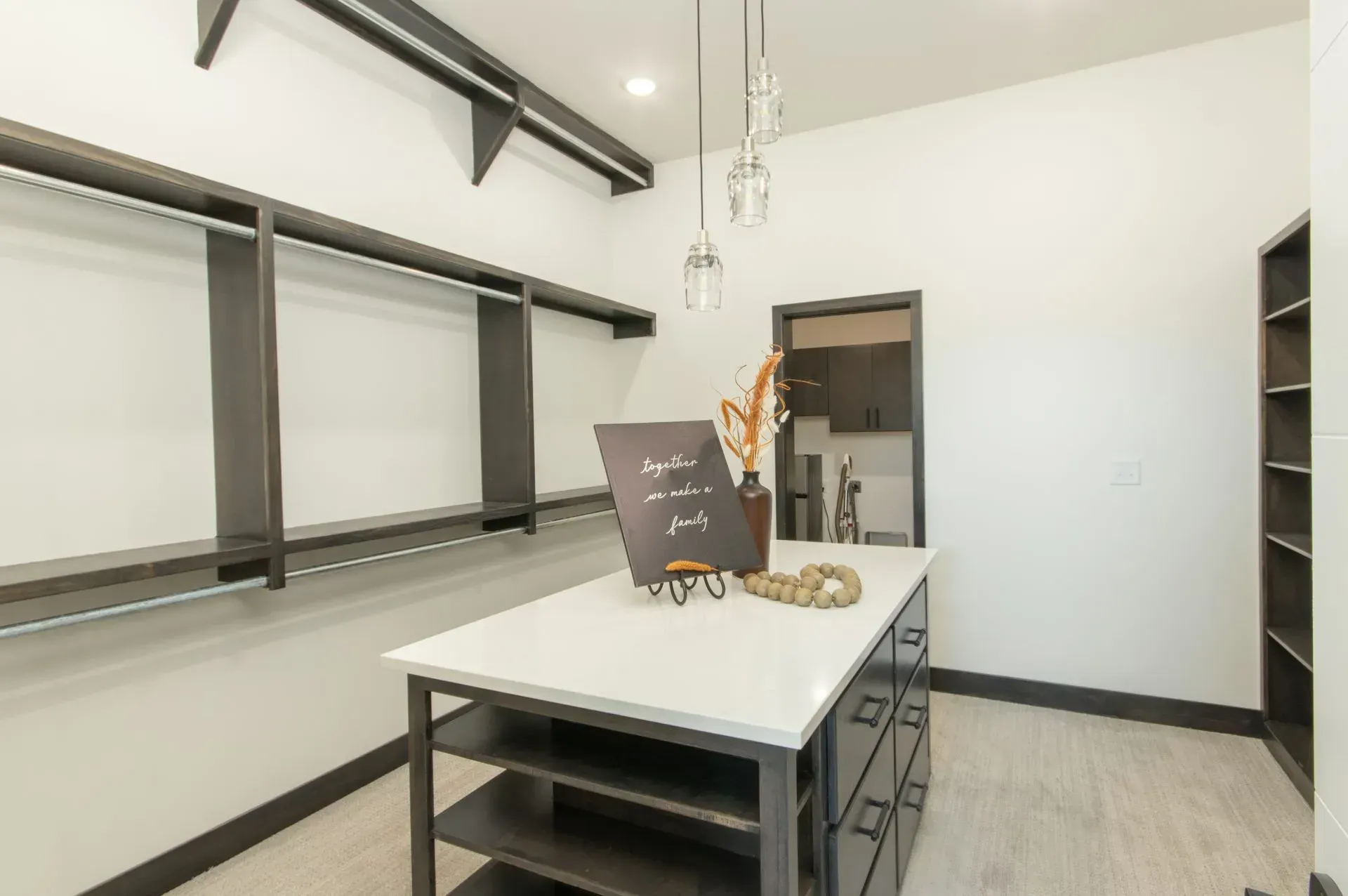 Modern kitchen with a white island, black stools, large windows, and pendant lights
