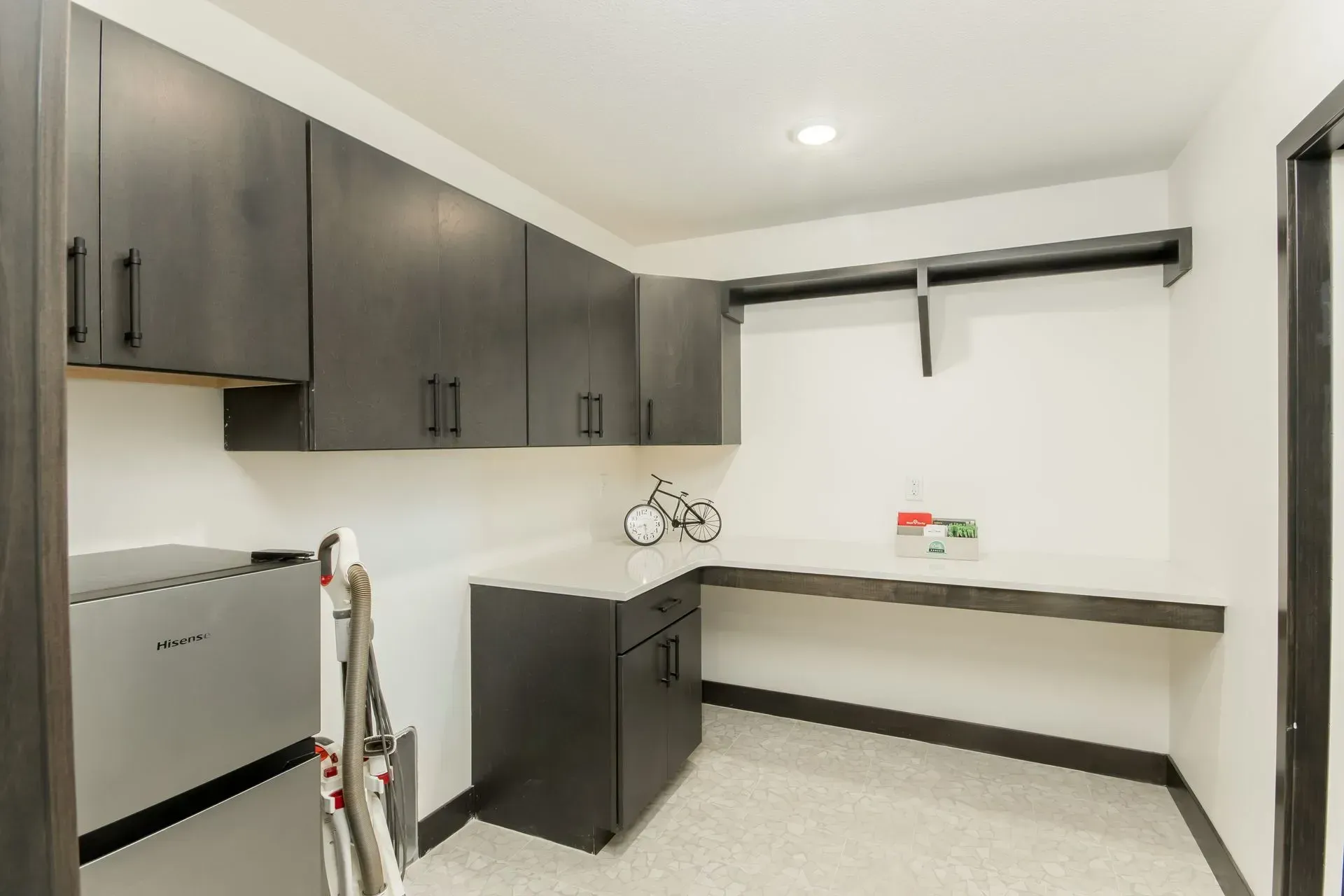 Compact utility room with gray cabinets, white walls, and a long workbench