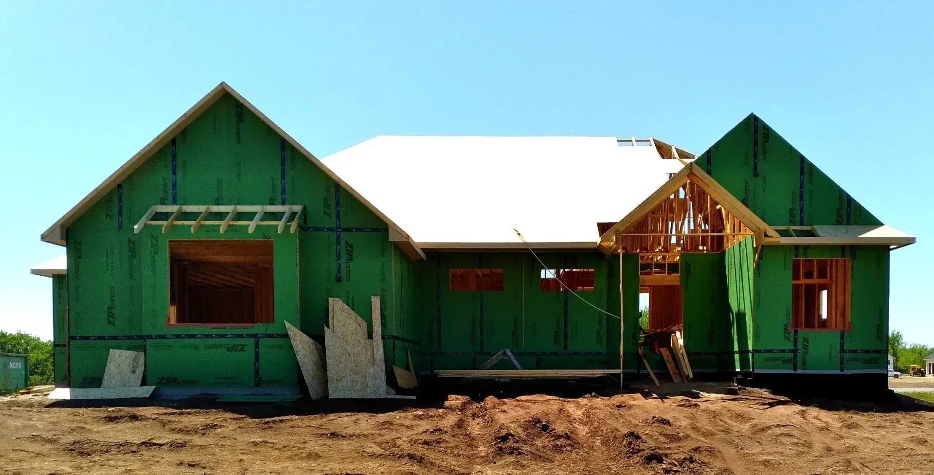 Green house under construction with white roof and unfinished wooden entryway