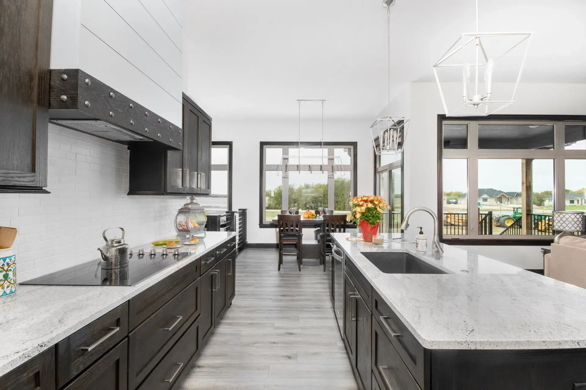 Modern black-and-white kitchen opening to a bright dining area and windows with a water view