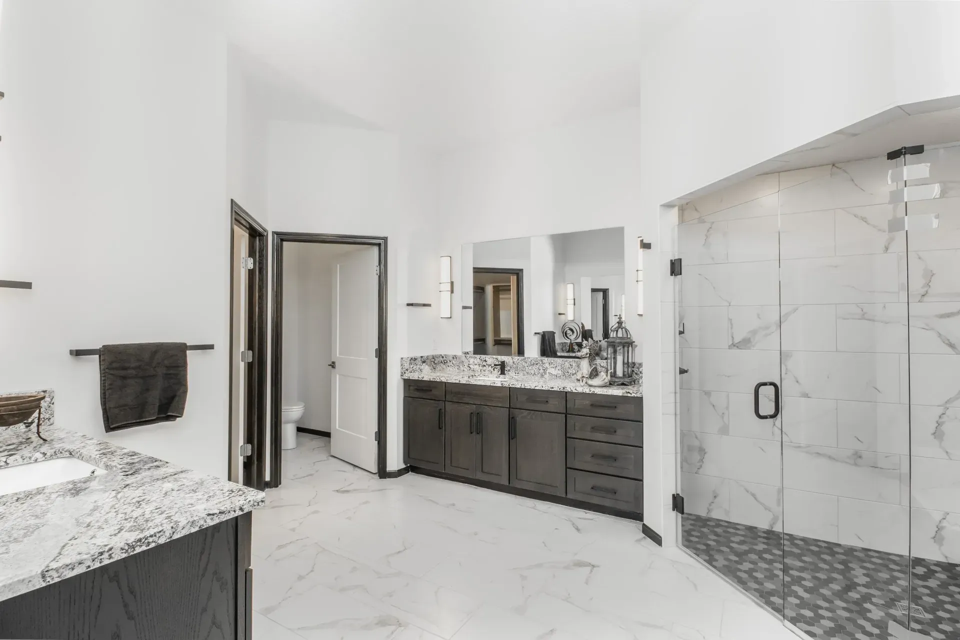 Modern white bathroom with double vanity, large mirror, and glass-enclosed shower.