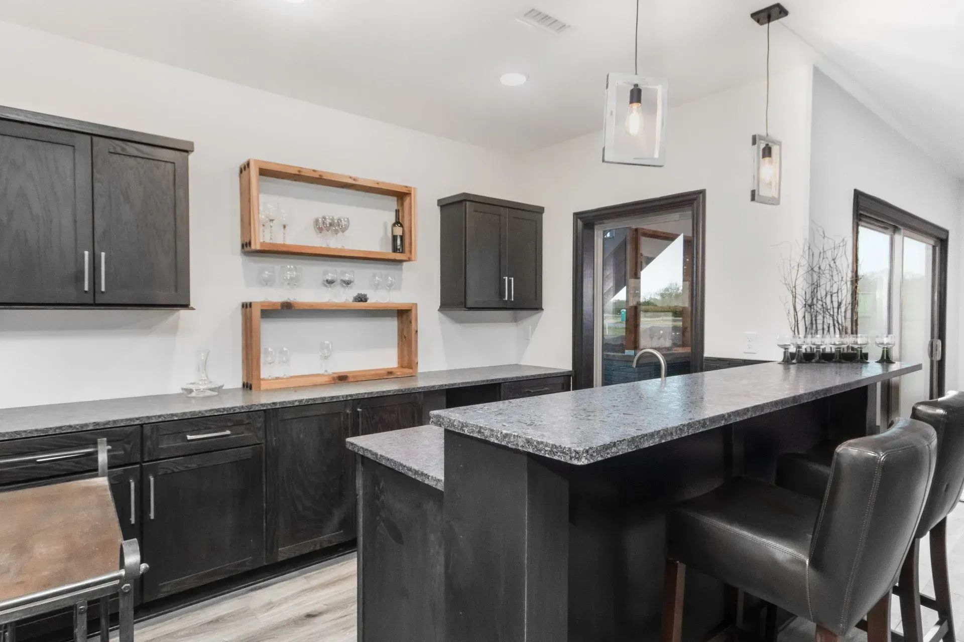 Modern kitchen with black cabinets, marble island, and black bar stools in a bright interior