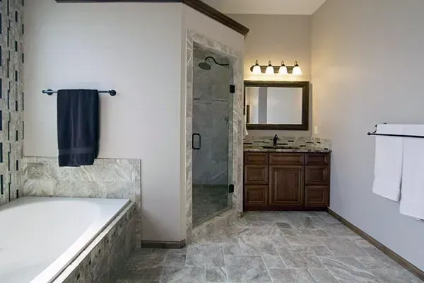 Accessible bathroom with bathtub, vanity, mirror, and grab bars in a tiled room