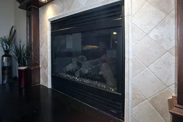 Black fireplace with glass doors set into a tiled wall in a living room