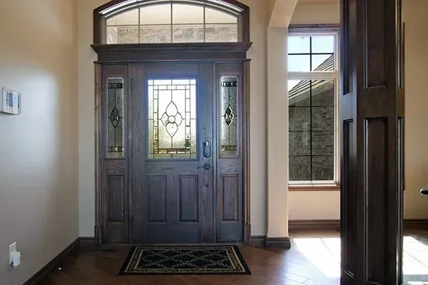 Front entry with dark wood double doors, glass panels, sidelights, and a small rug on hardwood floor