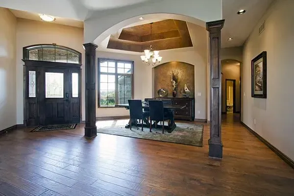 Spacious foyer and dining area with hardwood floors, arched ceiling, and dark wood furniture