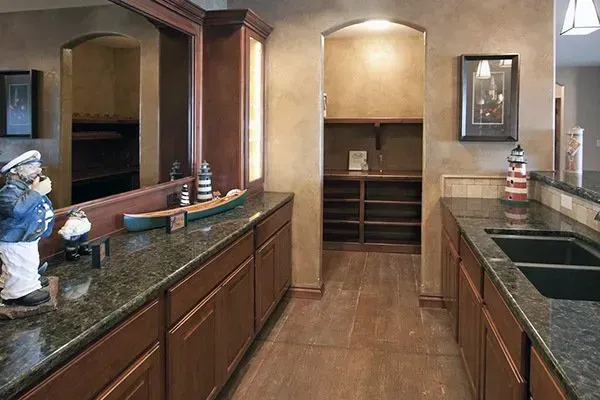 Spacious kitchen with dark granite counters, wood cabinets, and a central island with a sink.