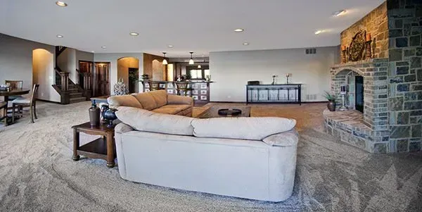 Spacious modern living room with beige sofa, stone fireplace, and open layout