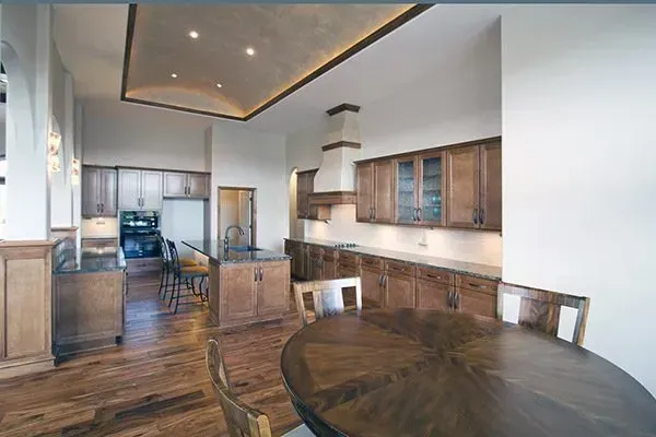Modern kitchen and dining area with wood cabinetry, round table, and recessed ceiling lights