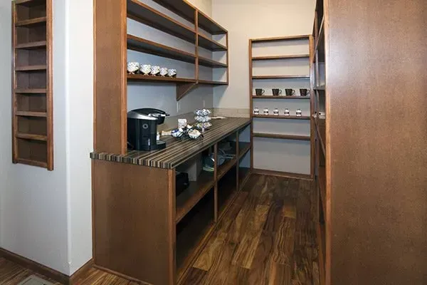 Modern coffee nook with wooden shelves, granite counter, and wood flooring in a narrow hallway area