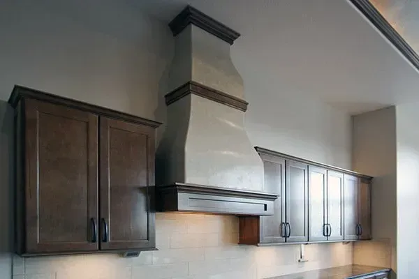 Modern kitchen wall with dark wood cabinets and a stainless range hood centered above the stove area