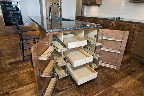 Kitchen island with open drawers and storage shelves, showing organized pull-out compartments and wooden floor