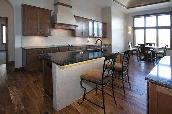 Modern kitchen with dark wood cabinets, island seating, and dining area by large windows
