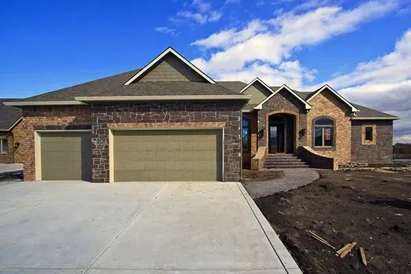New brick suburban house with two-car garage and concrete driveway under construction