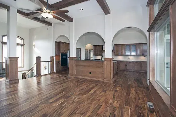 Spacious modern living room with wood floors, vaulted ceiling, ceiling fan, and arched kitchen pass-throughs