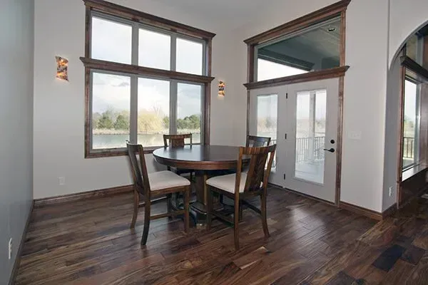 Dining nook with round table and four chairs beside large windows and a glass front door