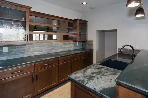 Modern kitchen with dark wood cabinets, granite island, and glass-front upper cabinets