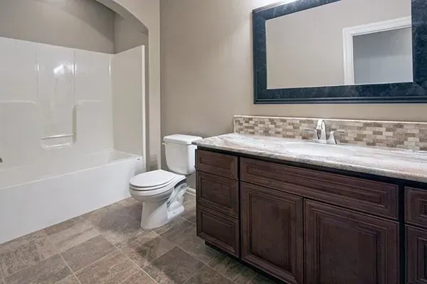 Modern bathroom with a bathtub, toilet, and dark wood vanity with large mirror