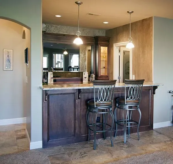 Modern kitchen with dark wood breakfast bar, two stools, and pendant lights.