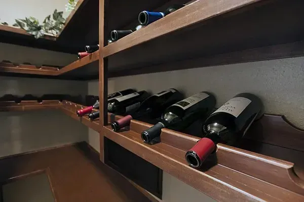 Bottles stored on wooden shelves in a dim pantry or cellar
