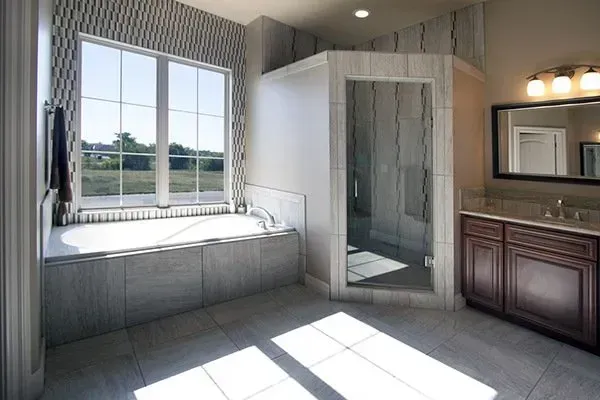 Modern bathroom with large window, freestanding tub, glass shower, and vanity with mirror.