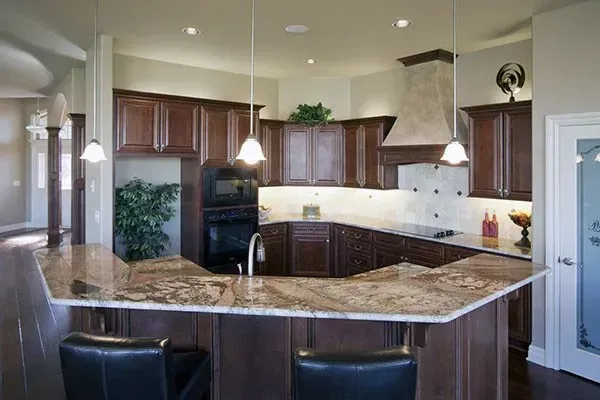 Modern kitchen with granite island, dark wood cabinets, pendant lights, and stainless-steel appliances