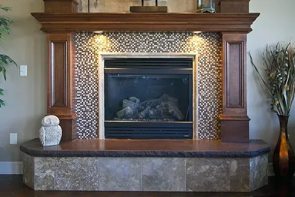 Fireplace with dark wood mantel, copper tile surround, and stone hearth in a living room