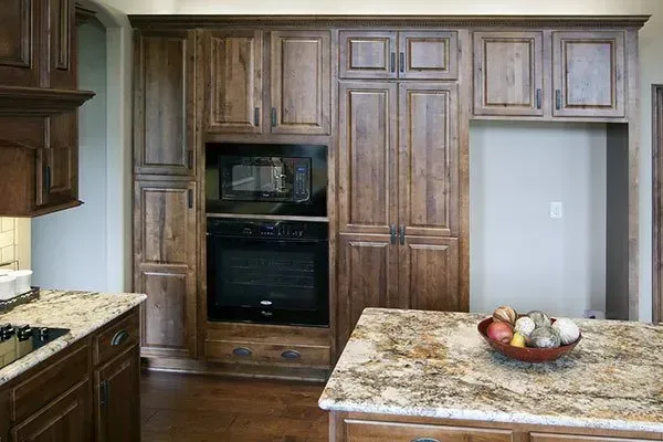 Kitchen with built-in wood cabinetry, stainless oven, granite island, and a recessed open wall space