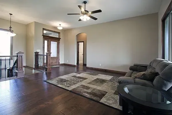 Spacious living room with dark wood floors, gray walls, ceiling fan, rug, and sectional sofa.