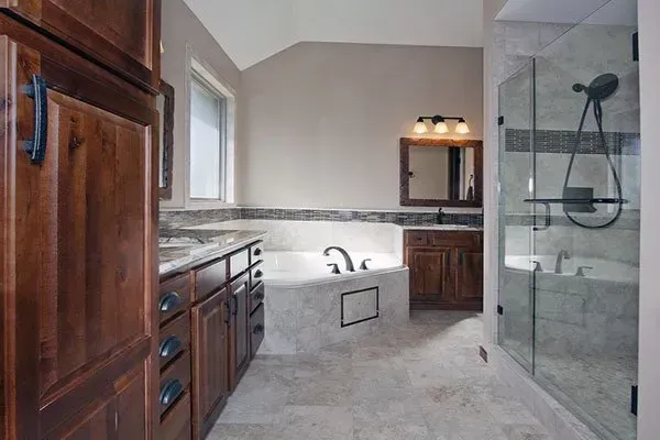 Spacious bathroom with wood cabinets, double vanity, large soaking tub, and glass walk-in shower.