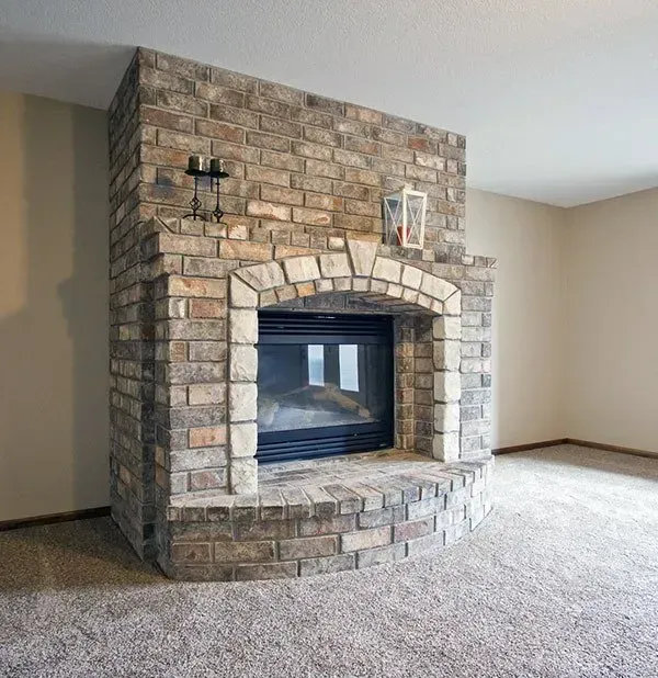 Stone fireplace with arched opening in a carpeted living room