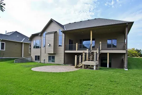 Suburban house with a raised deck and stairs overlooking a green lawn
