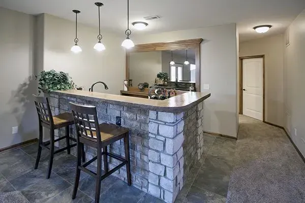 Modern kitchen with stone breakfast bar, bar stools, pendant lights, and hallway entrance