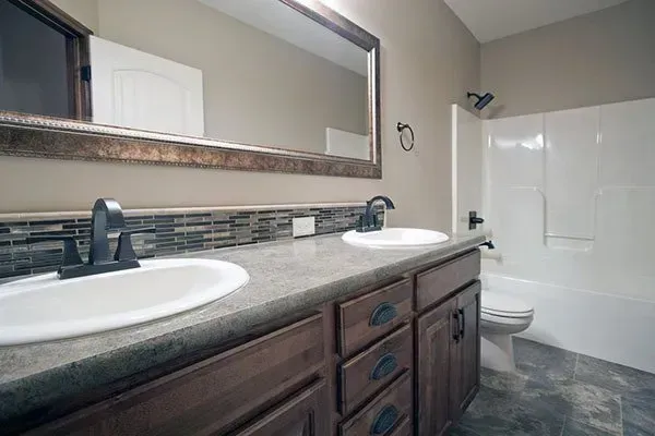 Modern bathroom with double sink vanity, large mirror, and white bathtub/shower