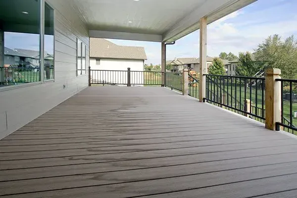Covered wooden porch with white siding, black railing, and view of neighboring houses
