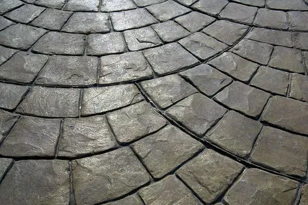 Curved gray stone paving with dark grout lines forming a cobblestone pattern